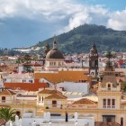 The historic centre of San Cristóbal de La Laguna reveals terracotta rooftops, colonial buildings, the Cathedral dome and La Concepción tower, framed by the green Anaga hills.