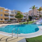 The pool with a waterslide at the 4-star Servatur Isora Suites creates a cheerful space for families, surrounded by green areas, palm trees and the resort’s bright buildings in Puerto de Santiago.