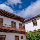 An elegant colonial courtyard in San Cristóbal de La Laguna is framed by whitewashed walls, wooden windows and a long Canarian balcony overlooking an intimate, sunlit patio.