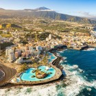 Aerial view of Puerto de la Cruz, featuring the Lago Martiánez bathing complex designed by César Manrique, the volcanic coastline and Mount Teide in the background.