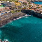 Playa de La Arena, in Puerto de Santiago, forms a bay of black volcanic sand washed by turquoise waters, surrounded by lava cliffs and tourist facilities overlooking the Atlantic.