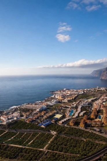 From above, Puerto de Santiago stretches between banana plantations and the ocean, while Los Gigantes closes the horizon with its imposing volcanic cliffs.