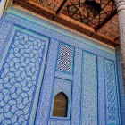 Nel Tash-Khauli Palace in Khiva, refined blue and turquoise majolica tiles cover walls and niches, alongside a precious carved wooden column, an exquisite expression of the art of the Khanate.