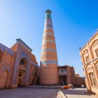 The Islam Khodja Minaret, the tallest in Khiva, dominates Itchan Kala with its elegant tapered silhouette, decorated with bands of turquoise majolica tiles, a symbol of the historic city.