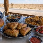 In the heart of the Kyzylkum, a roadside lunch features plov, samsa, shurpa, non bread and achichuk, accompanied by traditional Uzbek green tea.