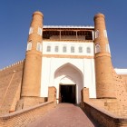 The monumental entrance to the Ark of Bukhara leads into the ancient citadel of the emirs, framed by imposing brick walls, towers and a ramp rising into the heart of the fortress.