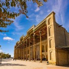 The Bolo Hauz Mosque, opposite the Ark of Bukhara, captivates with its portico supported by slender carved wooden columns and the richly decorated ceiling of its prayer hall.