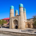 The Chor Minor Madrasa welcomes visitors with four towers crowned by turquoise domes, a symbol of 19th-century Bukhara and its ancient Quranic schools.