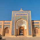 The grand portal of the Bakhouddin Naqshband Complex, decorated with mosaics and inscriptions, welcomes pilgrims and visitors into the spiritual heart of sacred Bukhara.