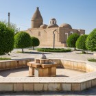 In the garden of the Chashma Ayub Mausoleum, pools and trees lead the eye towards the domes, including the distinctive conical one inspired by Khorezmian tradition.