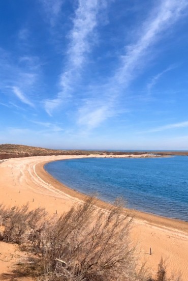 In the Kyzylkum Desert, Lake Aydarkul meets a long golden beach: blue waters and shrub-dotted dunes create a surprisingly beautiful natural landscape.