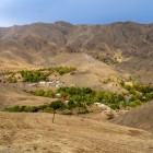 Before the traveller, the Nuratau Mountains frame a small village: houses and green gardens follow the water, revealing the simplicity of rural life among these arid valleys.