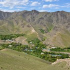 From above, Ukhum appears as a small oasis: houses and trees follow the water at the foot of the Nuratau Mountains, creating a striking contrast with the arid, rocky slopes.