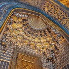 Entering the Sher-Dor Madrasa, the gaze rises towards the elaborate muqarnas, where geometric patterns, inscriptions and golden details reveal the richness of the interior.