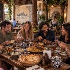 After visiting Khast-Imam, the group stops for lunch at a restaurant in Tashkent, sharing Uzbek dishes before continuing their tour of the city.