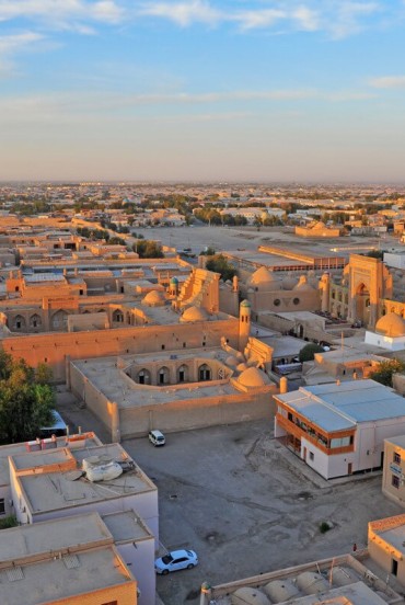 The journey leaves Khiva behind with a view of its historic neighbourhoods and earthen architecture, beginning the long transfer across Khorezm towards Bukhara.