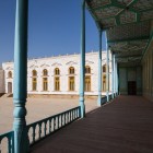 The route enters the palace courtyard, where a long portico with blue columns connects the court rooms amid geometric ceilings and the complex’s white façades.