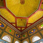 The visit concludes beneath a ceiling decorated with vibrant local geometric panels and polychrome glass, combining Uzbek craftsmanship with European influences.