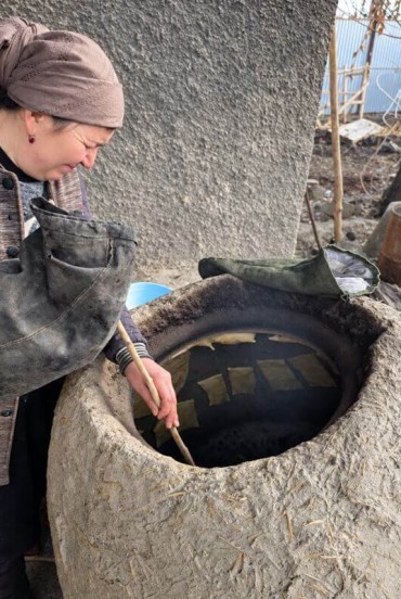 The hostess prepares lunch in a large kazan set into an earthen hearth, demonstrating a traditional cooking method still preserved in the everyday family cuisine of the village.